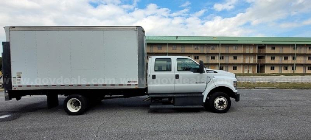 Medium-duty box truck profile shown in side view. White cab and box with no visible branding. Side text watermark from govdeals.com across the image.