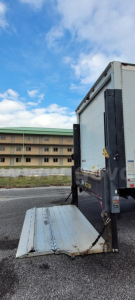 Truck rear with loading ramp extended showing box truck bed and rear liftgate on a Ford F-650 with blue sky.
