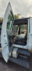 Ford F-650 cab step entry with open rear passenger door showing interior seating and box truck exterior.