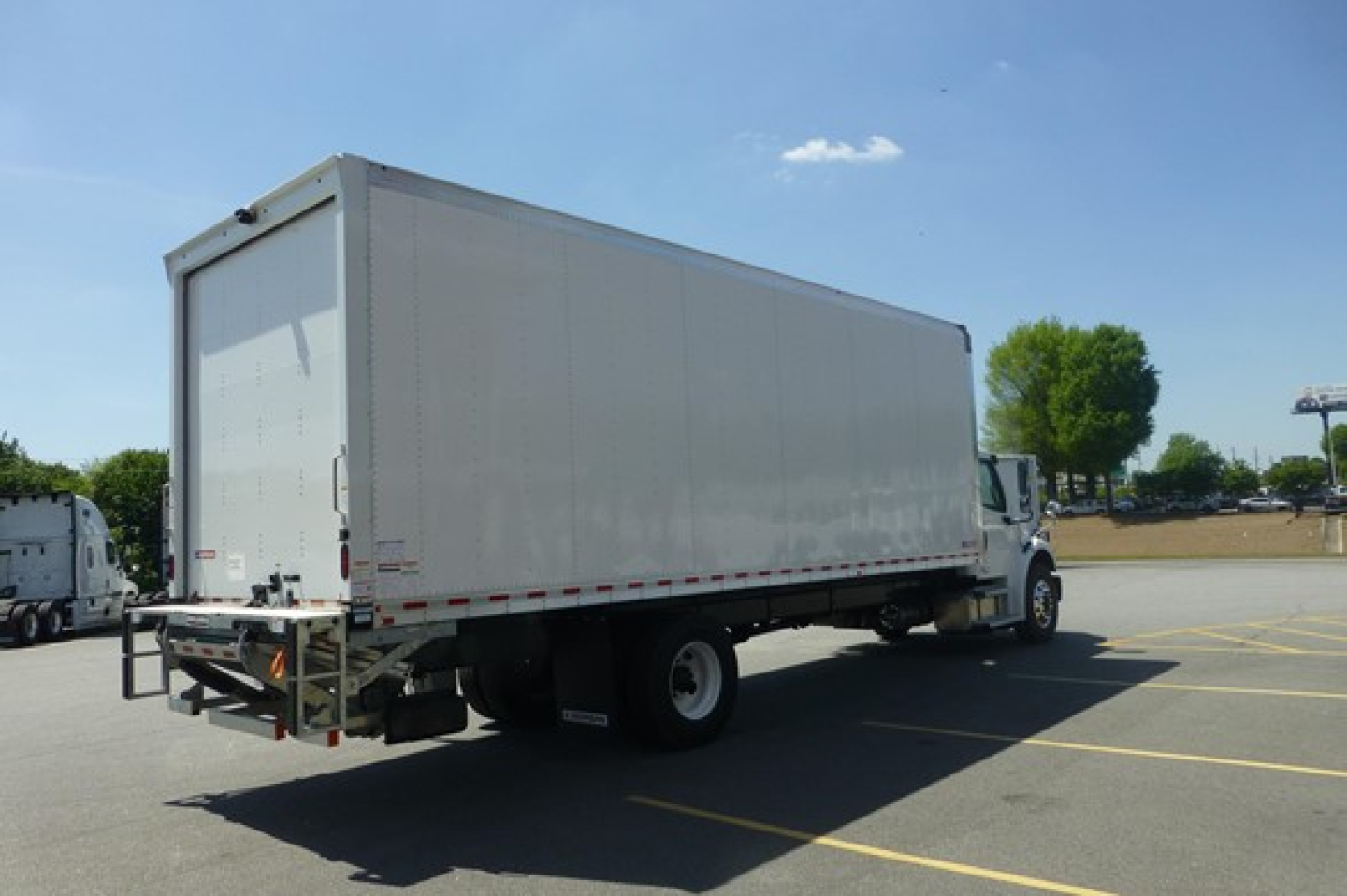 Box truck rear-left view showing cargo box and cab on a Freightliner M2 106 Plus chassis.