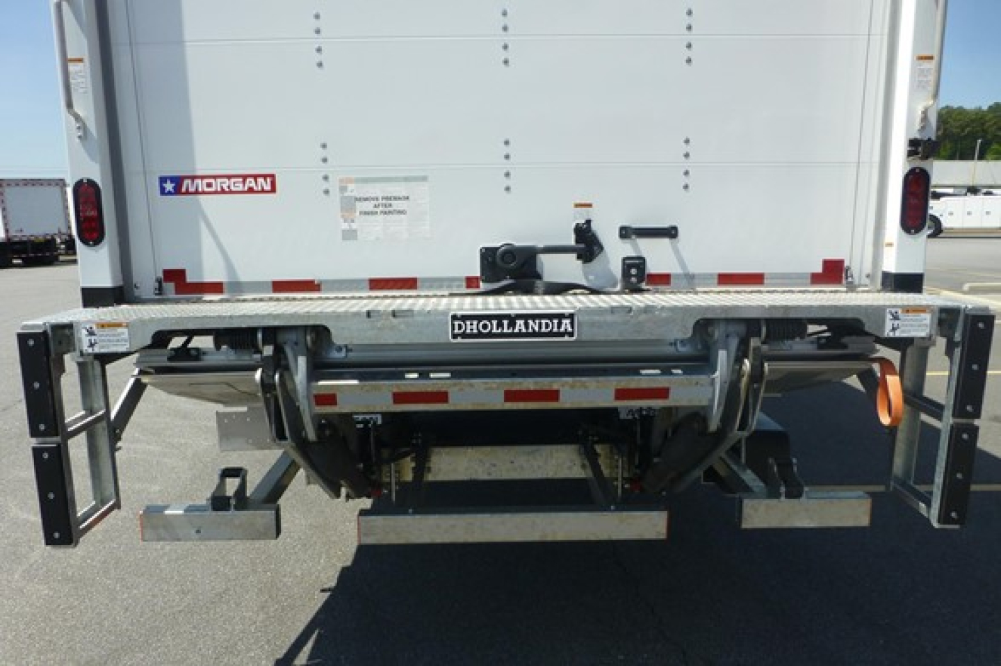 Rear view of a Freightliner M2 106 Plus box truck showing Dhollandia hydraulic liftgate and Morgan brand sticker, with taillights and reflective tape.