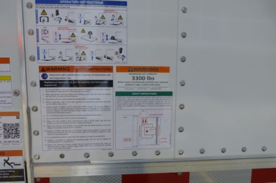 Truck side panel with operation instructions and warning labels, including 3300 lbs weight graphic, on Freightliner M2 106 Plus.
