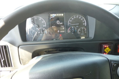 Dashboard view of Freightliner M2 106 Plus interior showing instrument cluster and steering wheel. Center display lit with 0 mph and various gauges.