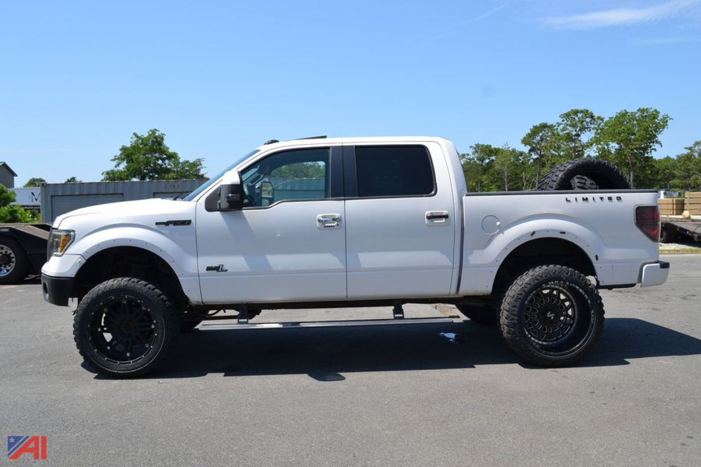 Ford F-150 Crew Cab pickup truck side view showing white body, black wheels, lifted suspension, and spare tire mounted in bed.