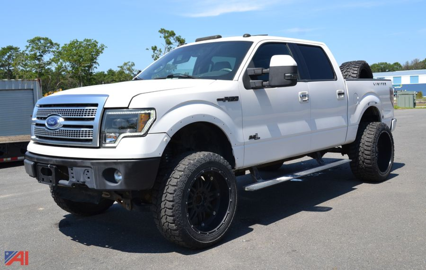 Ford F-150 pickup truck crew cab 4x4 white with raised suspension and large off-road tires, front view angled with spare tire on bed.