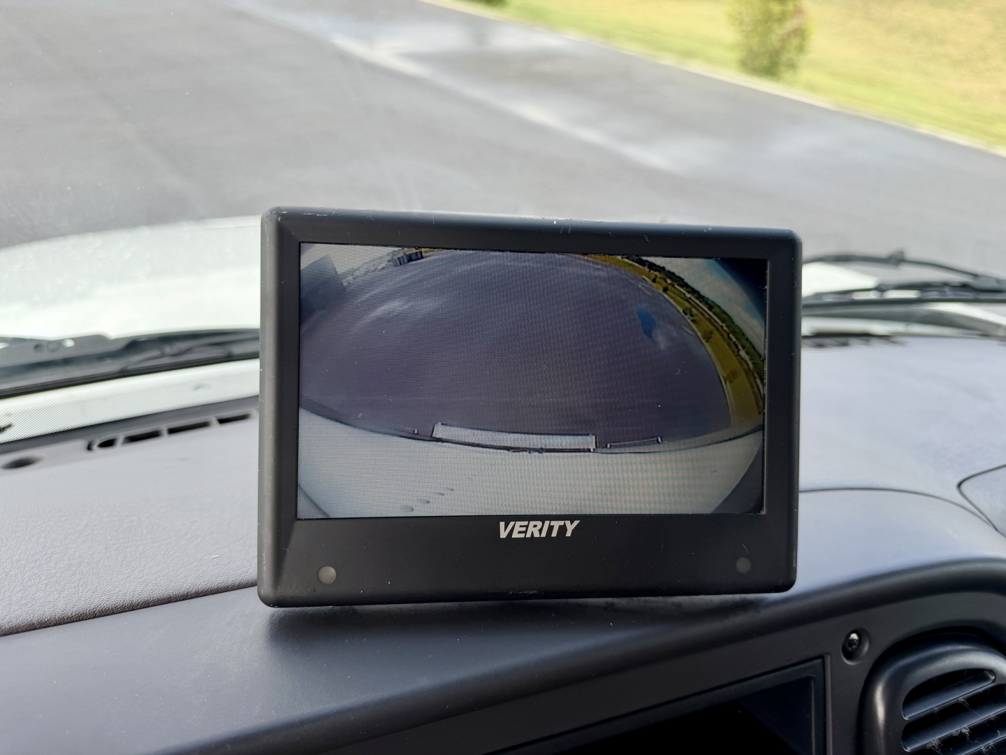 Verity brand small convex camera monitor displaying vehicle backup camera view mounted on a Freightliner M2-106 dashboard.
