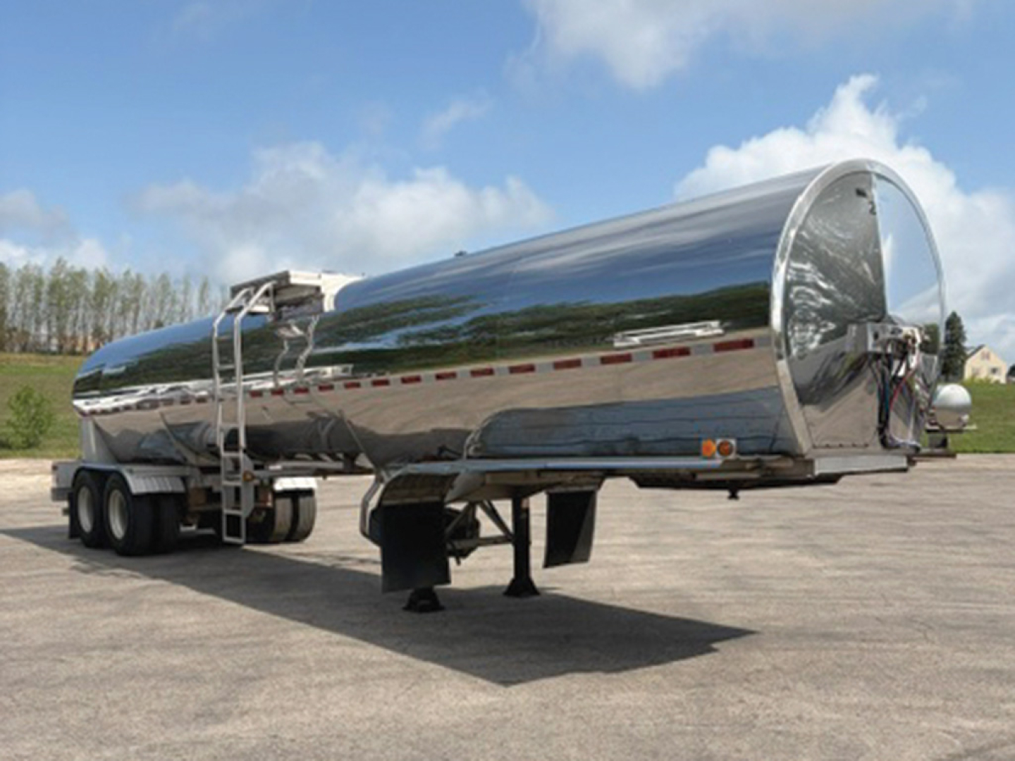 Tanker trailer by Brenner with polished stainless steel finish, triple-axle rear and hitch, showing curved cylindrical tank and landing gear.
