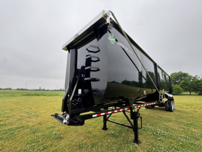 Dump trailer showing Armor Lite logo, black side, 40' x 100" dimensions, rear access ladder, in-service condition, roadside grass field.