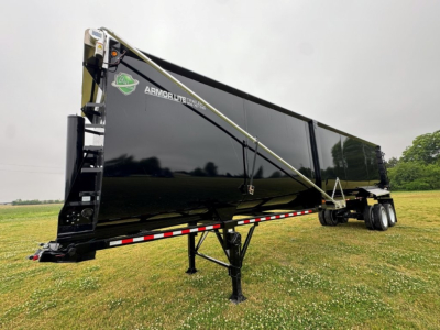 Armor Lite trailer showing side view with black finish, green and white logo, step tongue, and dual axle. Visible text: ARMOR LITE TRAILERS near the front.