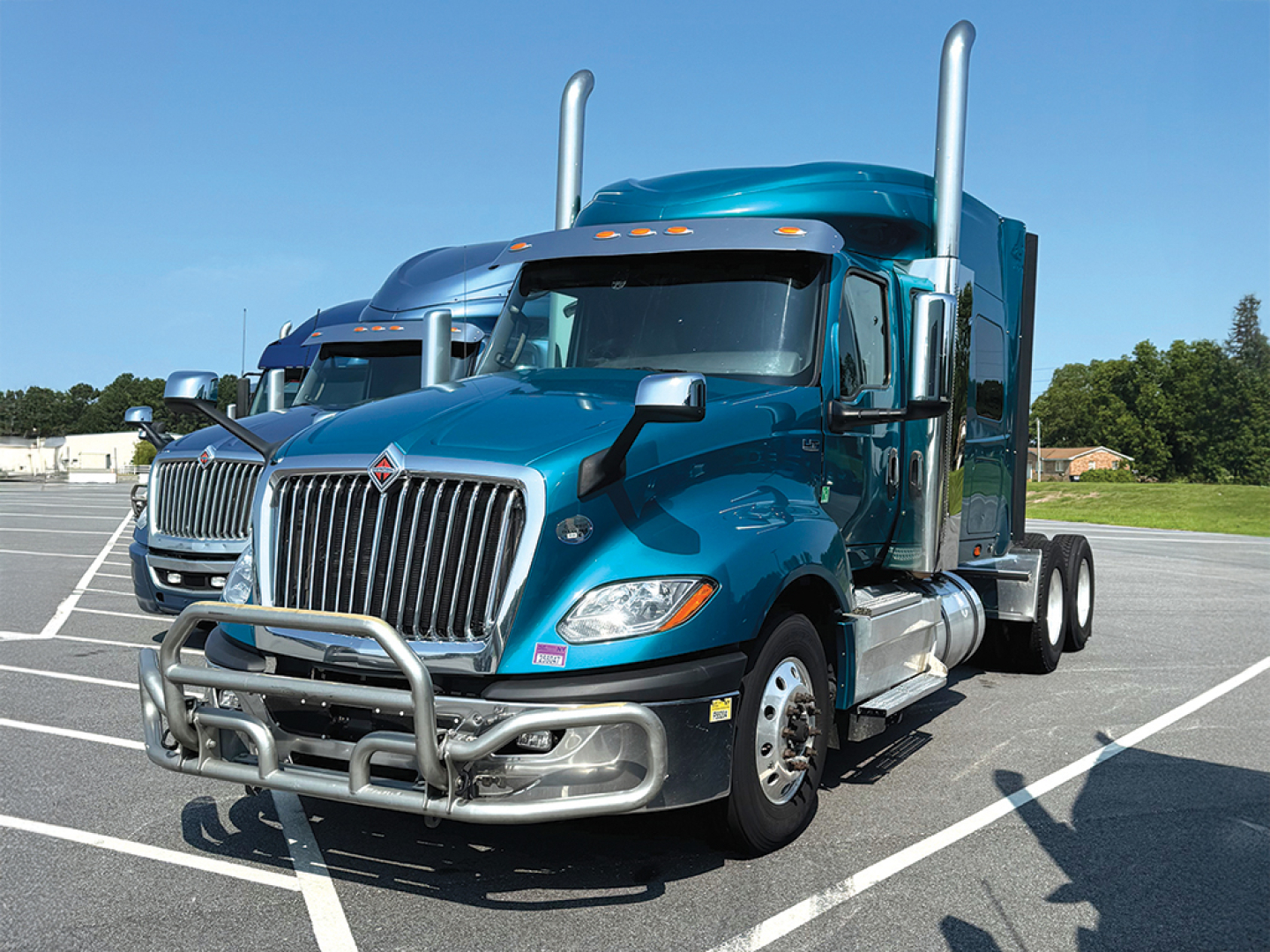 Truck cab and front of a teal 2020 International LT625 sleeper tractor in a parking lot.