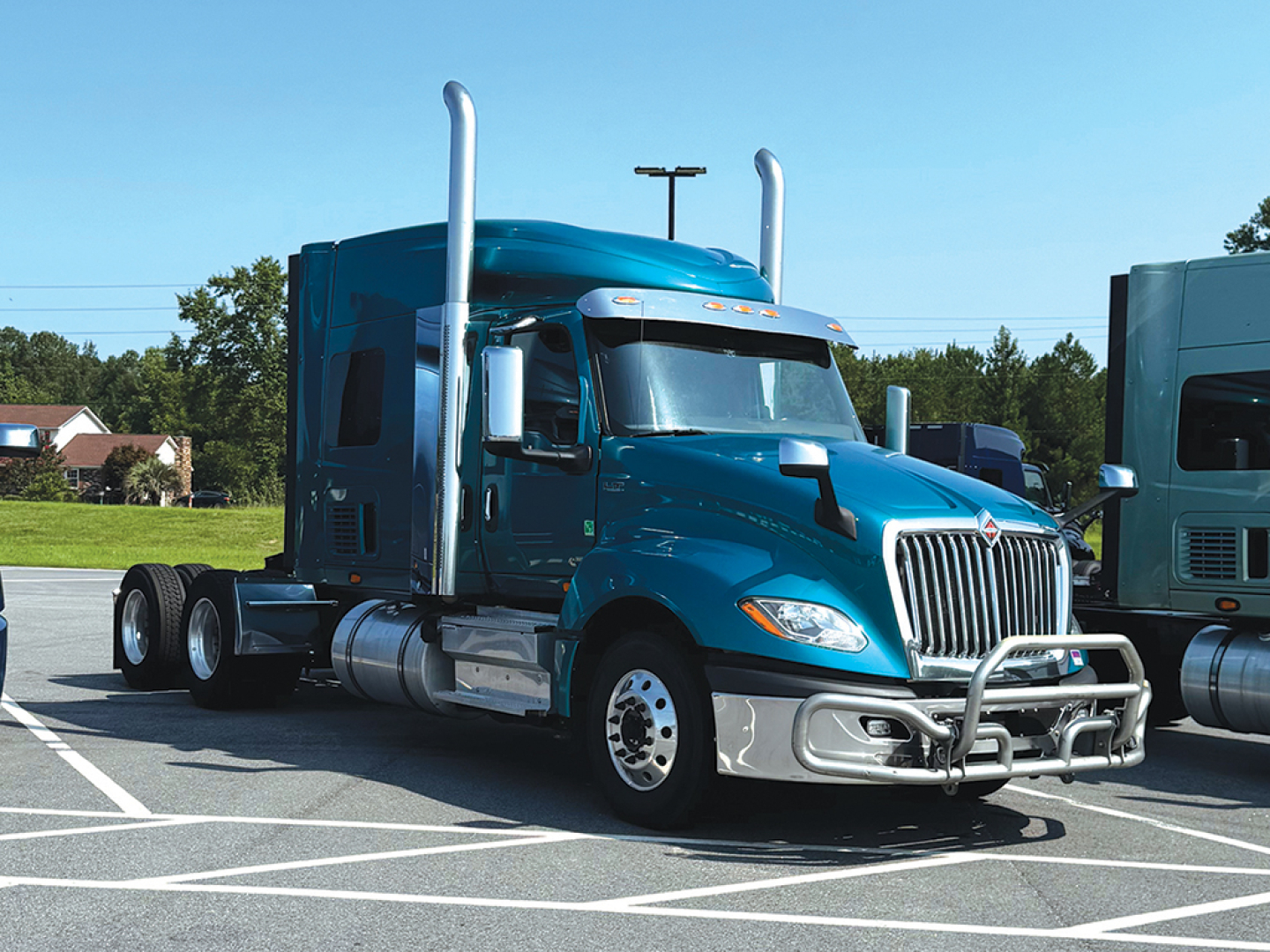 Truck cab in blue with chrome bumper and grille, International LT-series sleeper cab, dual exhaust stacks, chrome fuel tanks, parked in lot.
