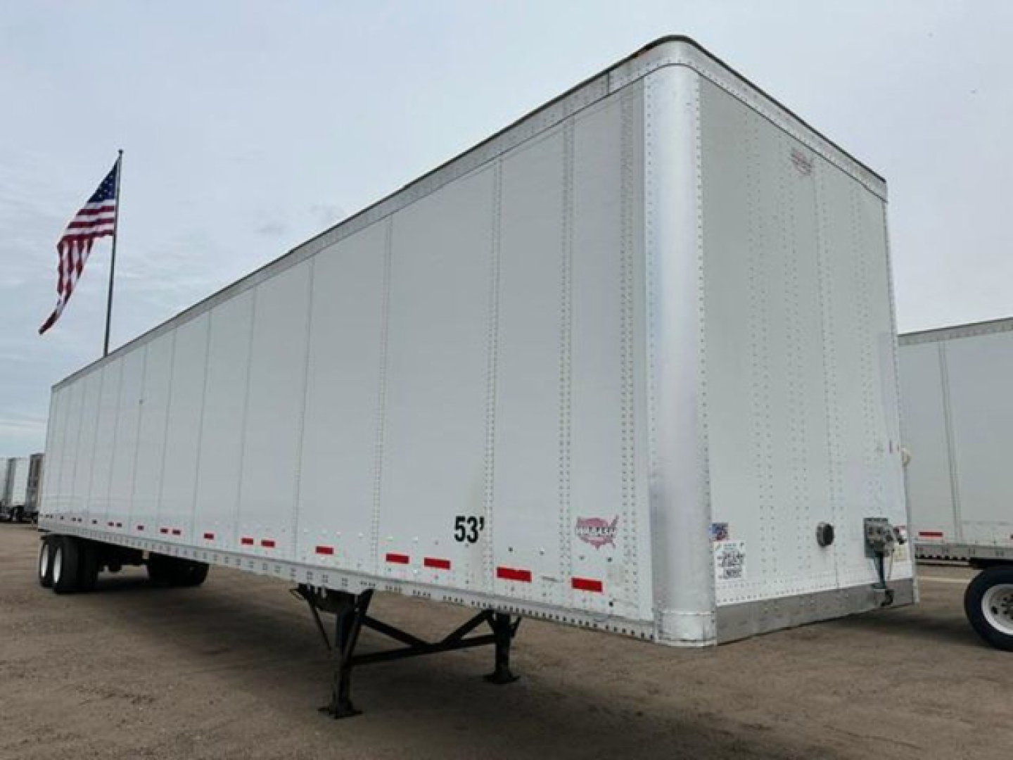 Trailer side view of a 2014 Wabash van trailer showing a 53' aluminum exterior with warning placards, rear door area, and support legs in the front. VIN visible, stock U90818.