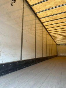 Trailer interior showing empty long cargo van with wooden floor and side walls, no equipment visible.