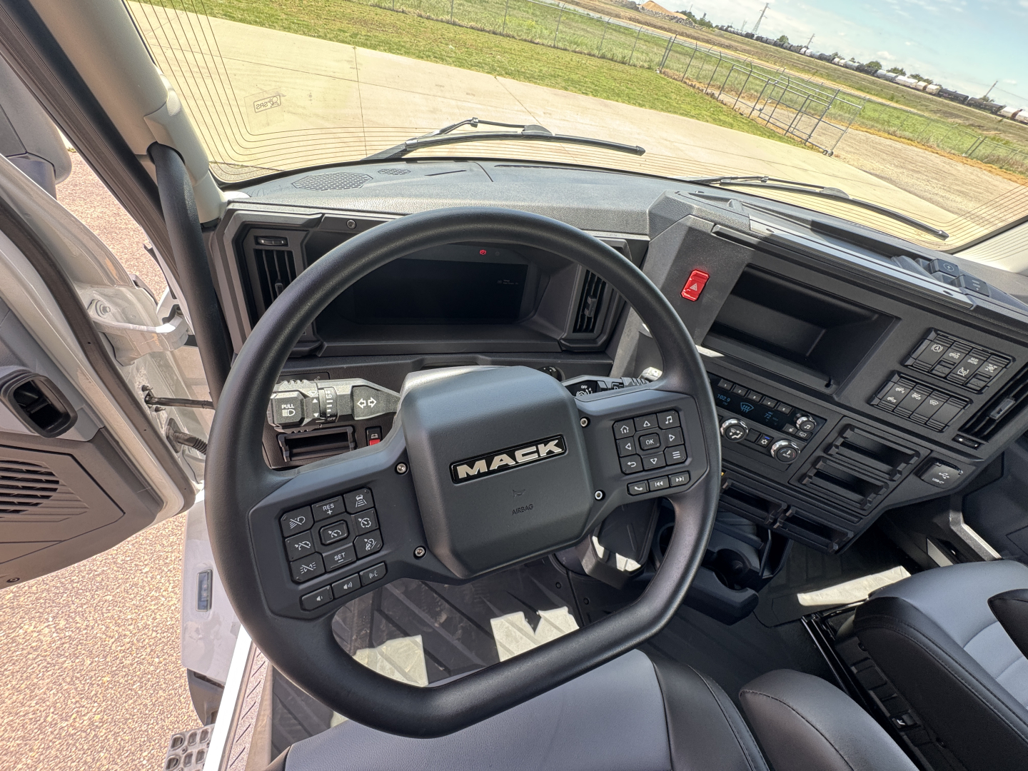 Mack AN64T truck cockpit showing steering wheel and dashboard controls and instrument cluster.