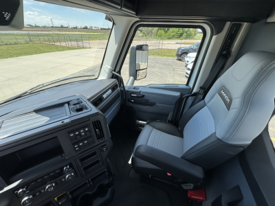 Cab interior of a 2027 Mack AN64T daycab showing steering wheel, dashboard, and two-tone gray seats with Mack logo on seat.
