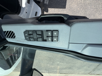 Truck interior left door control panel with window and mirror switches visible; dashboard area and windshield edge in view.