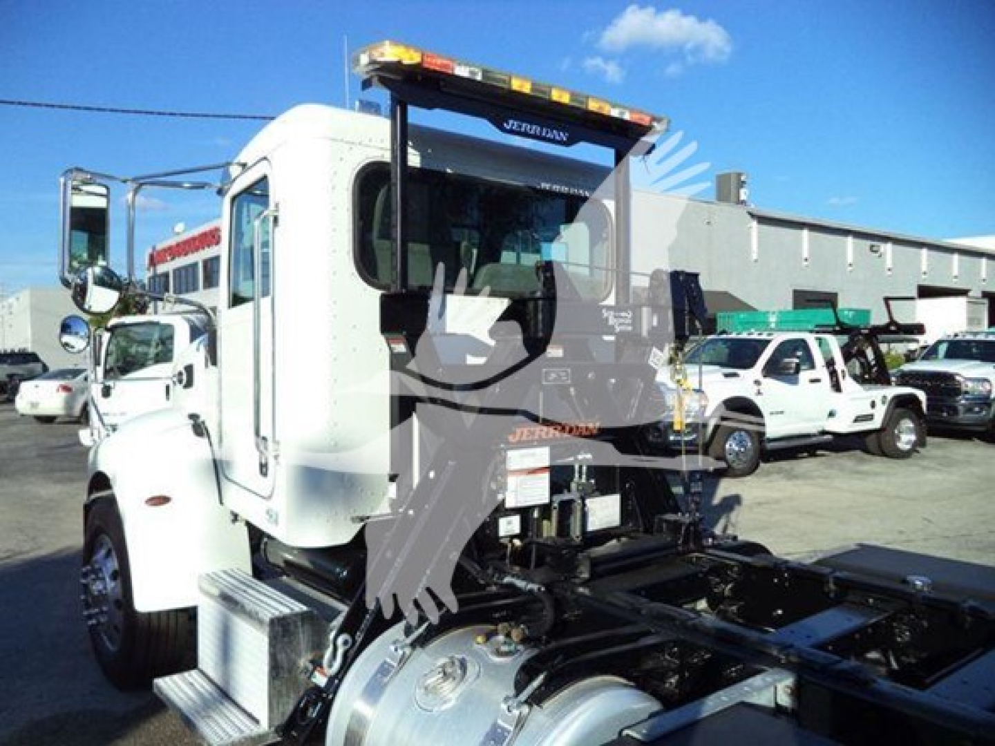Truck cab with rollback tow setup showing UREX? brand on light bar and Peterbilt style white cab; some black metal chassis and rear hydraulic components visible.