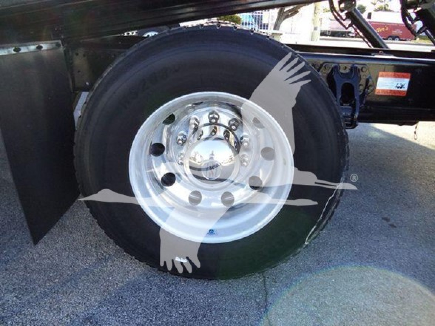Peterbilt truck wheel and tire assembly in view under a rollback truck, with metal fender and wheel hub visible.