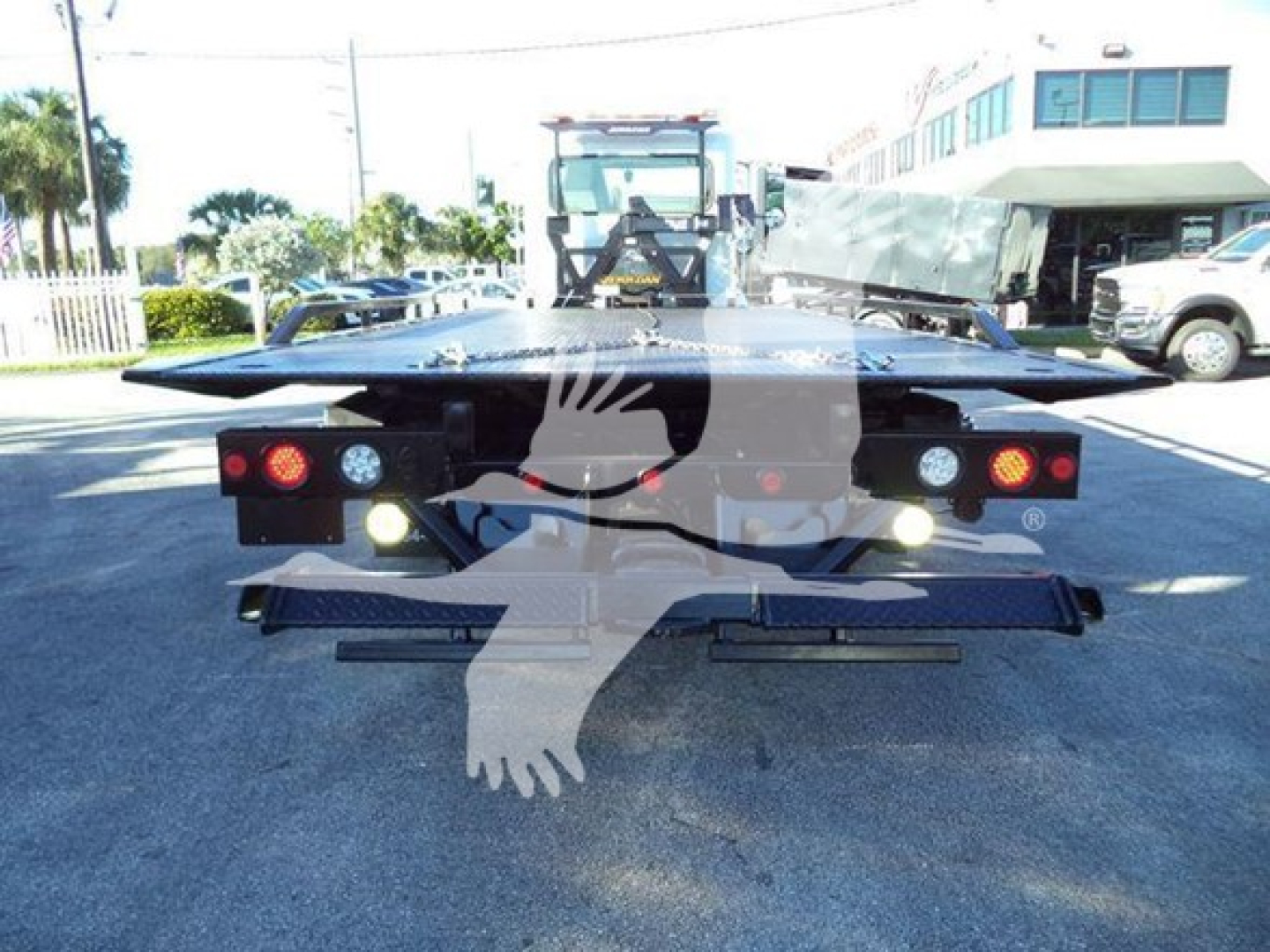 Peterbilt 337 rollback truck viewed from the rear showing tow bed and lights in a dealership yard.