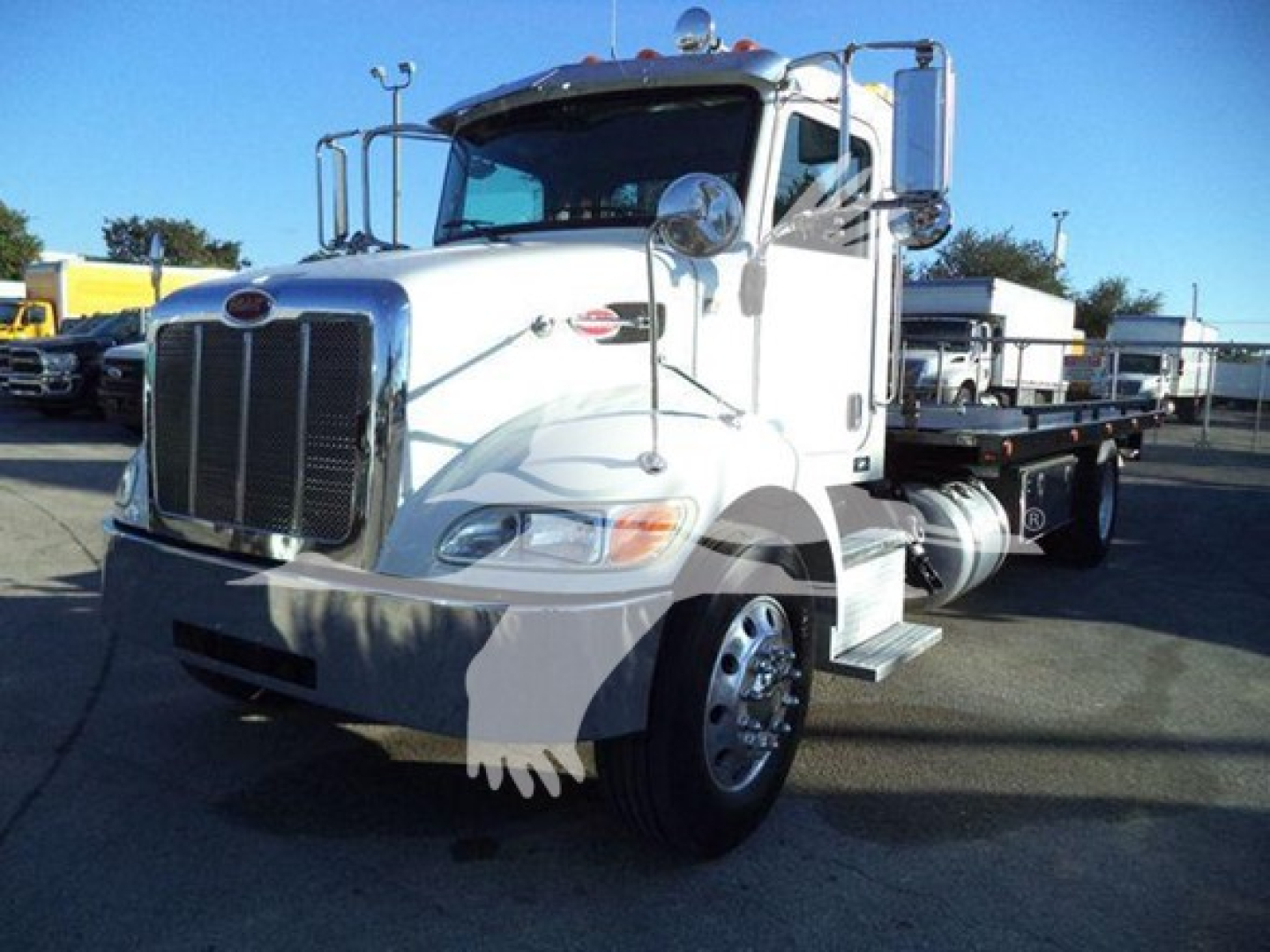 Peterbilt 337 rollback truck in readable view showing front grille, cab, and dual exhaust; white exterior; standard front bumper and headlamps.