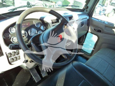 Vehicle cockpit showing steering wheel and dashboard of a Peterbilt 337 Rollback truck interior.