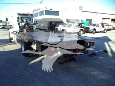 2020 Peterbilt 337 rollback truck in lot with flatbed, rear view showing lights and ramp. Visible text on plate or branding not legible.