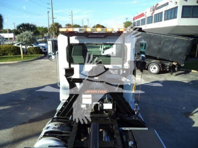 Peterbilt 337 rollback truck cab and chassis, front view with equipment, dealership lot in background.