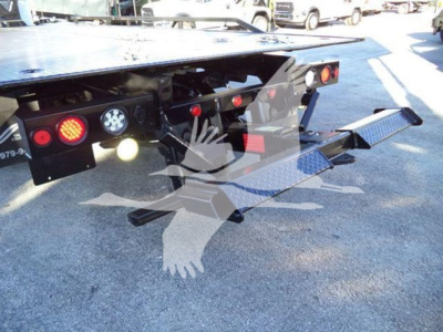 Rear view of a rollback tow truck with dual hydraulic ramps and multiple lights, platform in raised position.
