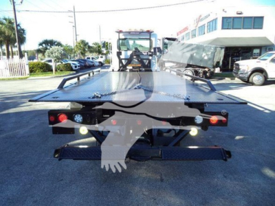 Truck bed of a rollback tow truck showing rear lights and equipment mounts.