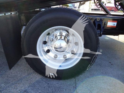 Peterbilt truck wheel and tire assembly in view under a rollback truck, with metal fender and wheel hub visible.
