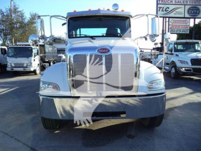 Peterbilt 337 rollback truck front view with large chrome grille, Peterbilt emblem, two side mirrors, and headlight clusters; dealership lot in background.