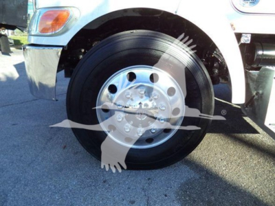 Peterbilt truck front wheel showing steel hub and black tire, portion of front fender and bumper