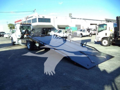 Peterbilt 337 rollback tow truck with deployed flatbed, side view showing loading ramp and cab, used condition.