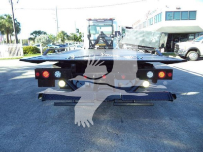 Peterbilt 337 rollback truck viewed from the rear showing tow bed and lights in a dealership yard.