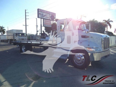Peterbilt 337 rollback truck showing cab and flatbed with company lot background.