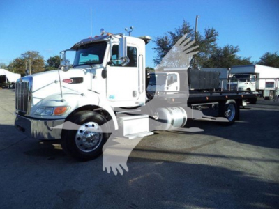Peterbilt 337 rollback truck showing white cab and flatbed with chrome fuel tanks and dual rear wheels.