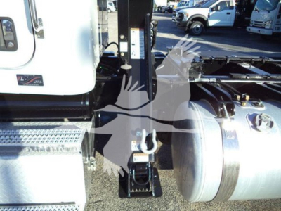 Peterbilt 337 rollback truck chassis showing fuel tank and hydraulic components with branding, rear wheel, and lifting apparatus in view.