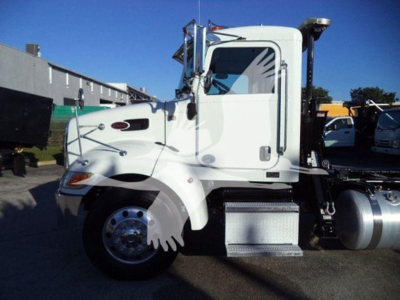 Truck cab of a white 2020 Peterbilt 337 side view showing chrome step and fuel tank with side mirror and door handle.