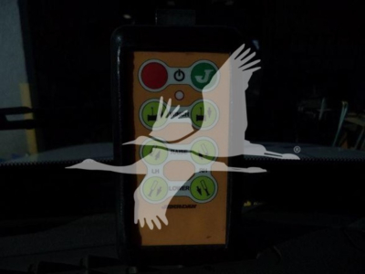 Remote control with colored buttons on orange body, labeled icons; overlaid white silhouettes of birds. The device shows a layout of circular colored buttons with symbols.