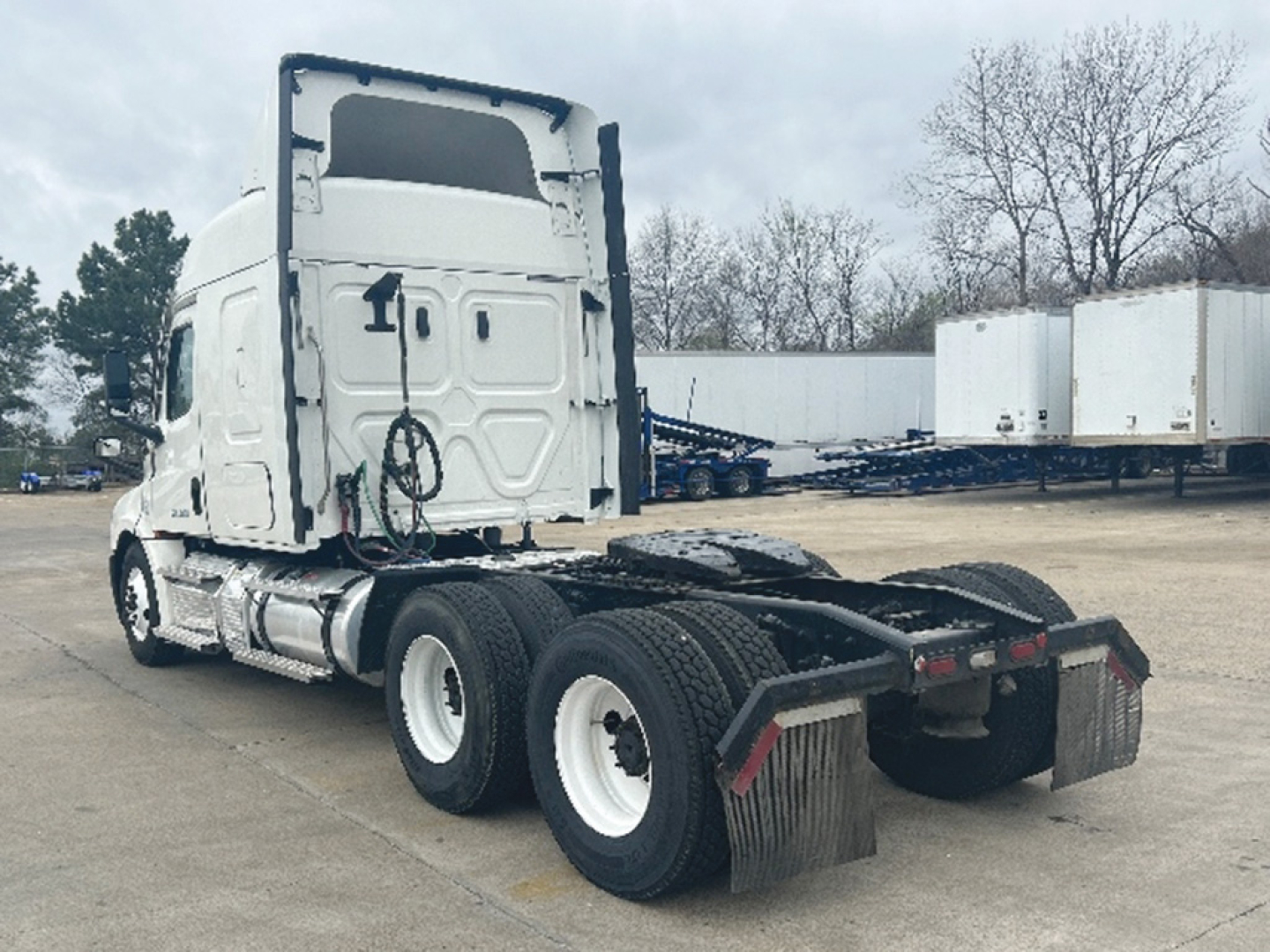 Tractor-trailer cab rear/side view showing Freightliner Cascadia 126 chassis with dual rear axles, mud flaps, and sleeper cab.