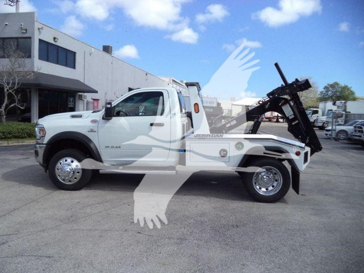 Ram 5500 truck with a winch bed, side profile view, white truck in dealership lot.