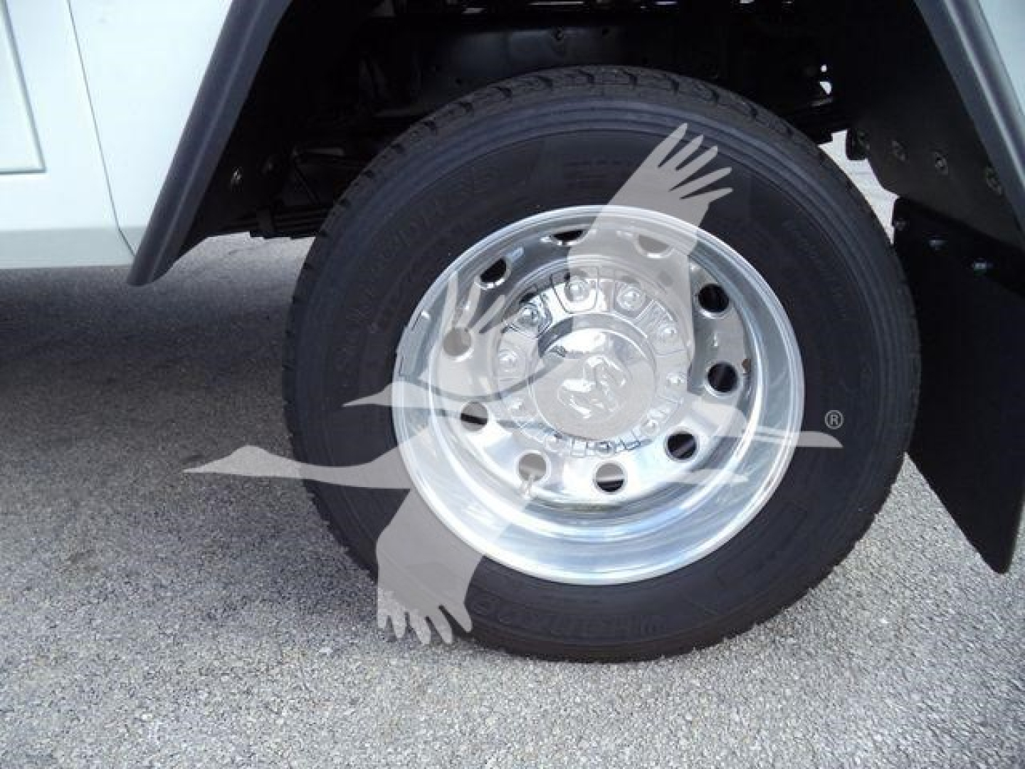 Wheel close-up on a white Ram 5500 SLT pickup showing polished steel hubcap and black tire, part of a truck front wheel assembly.