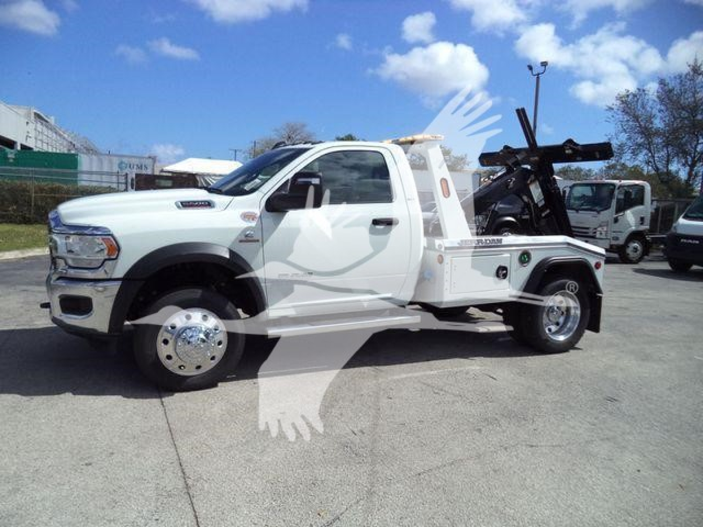 Ram 5500 pickup tow truck side view showing winch equipment and flatbed with hoist in service condition.