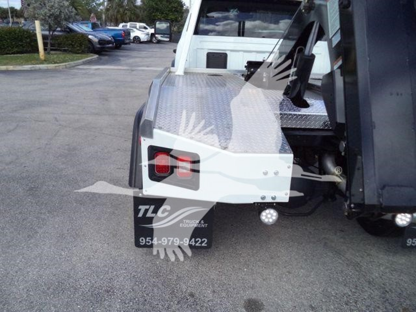 Truck bed rear view showing diamond plate toolbox, tail light, TLC truck equipment logo and contact number 954-979-9422.