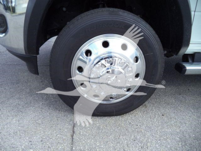 Wheel/tire close-up on a Ram 5500 front axle showing a polished chrome hubcap with lug nut holes and a Goodyear tire; partial fender and side step visible.