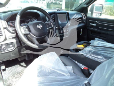 Ram 2024 Ram 5500 SLT interior view showing steering wheel with Ram logo, dashboard, touchscreen display, and front seats wrapped in protective plastic.
