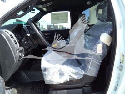 Vehicle interior of a 2024 Ram 5500 SLT showing front seats wrapped in protective plastic and dashboard area.