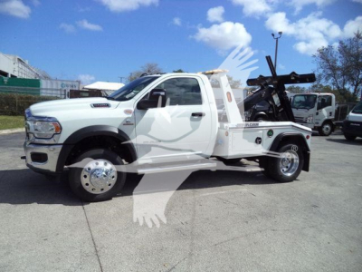 Ram 5500 pickup tow truck side view showing winch equipment and flatbed with hoist in service condition.