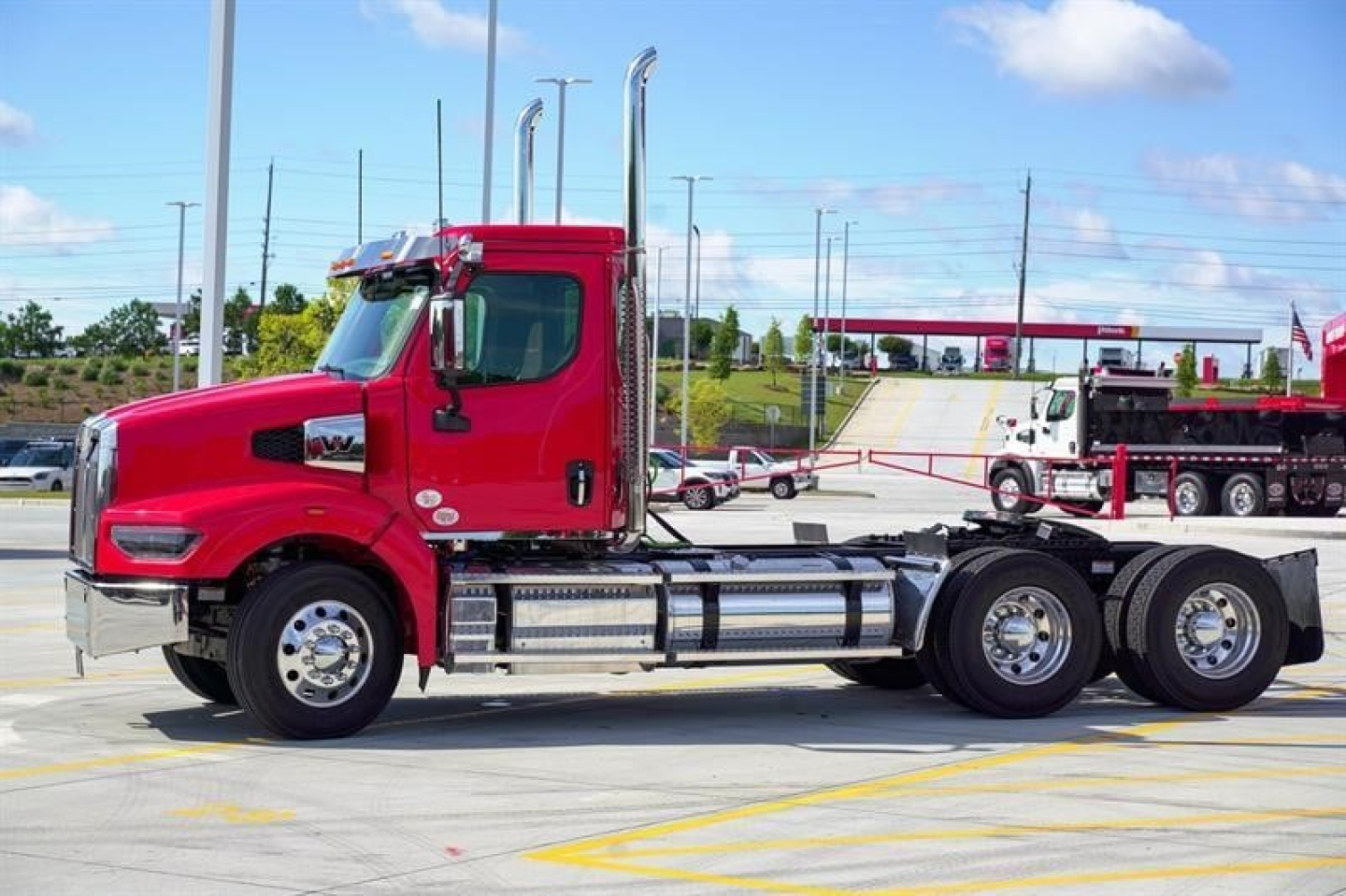 Red Western Star 49X day cab truck side view showing dual rear axles and chrome fuel tanks with chrome exhaust stacks.