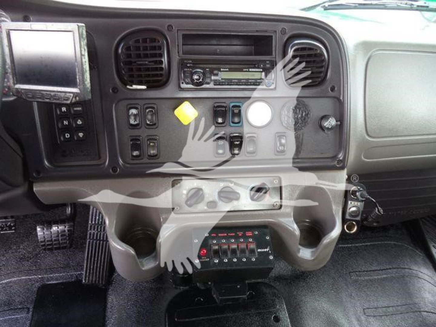 Dashboard of a Freightliner M2 106 cab showing radio, climate vents, control switches and pedal area.